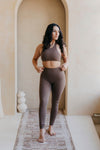 Woman in brown athletic wear standing in a room with an archway.