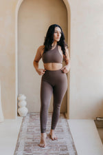 Woman in brown athletic wear standing in a room with an archway.