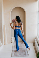 Woman in blue athletic wear standing in a room with archway and large window.