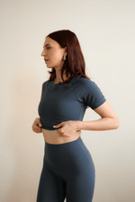 Woman wearing a dark blue athletic outfit against a plain background